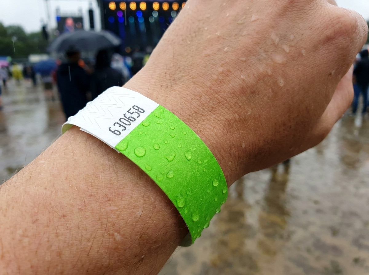 Identifikacijska zapestnica, nošena na zapestju v dežju na prostem festivalu, ki ponazarja odpornost na vodo in vlago